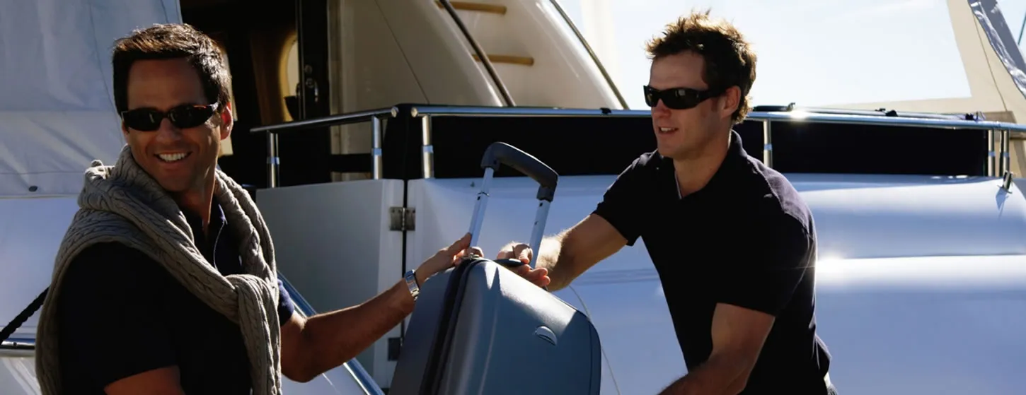 Men loading suitcase onto yacht